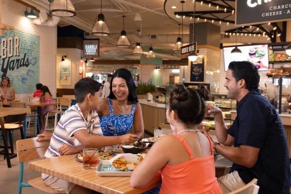 Family enjoying lunch with Saddle Creek Grill signage in the background at Harbor Yard Food Hall at Sunseeker Resort