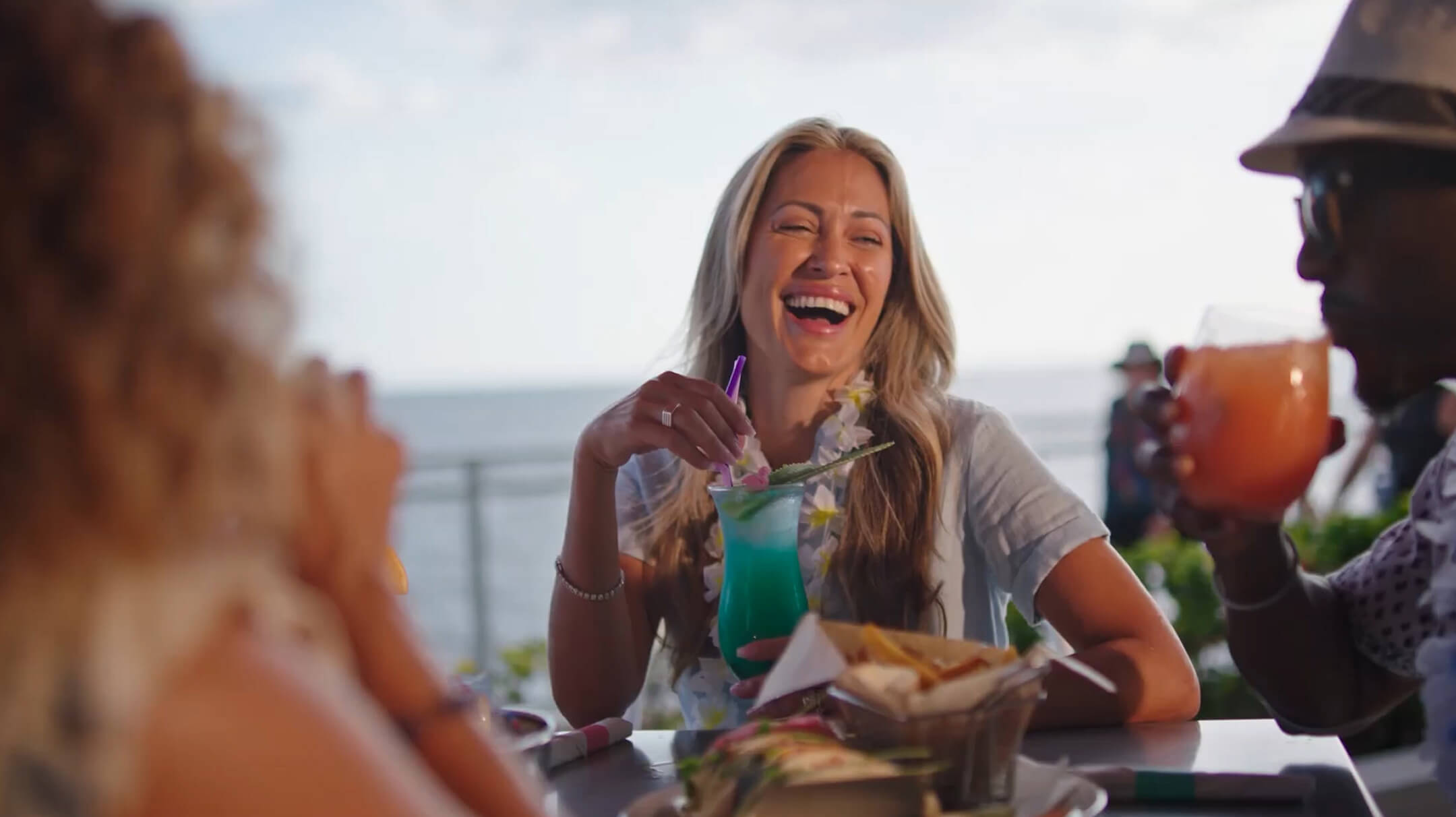 Woman laughing looking at a man as he takes a sip of his cocktail