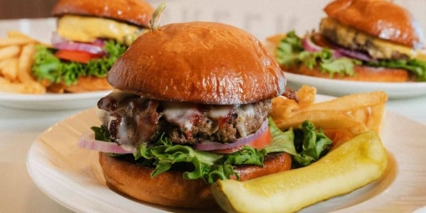 3 plates of burgers served with fries and pickle at Saddle Creek Grill