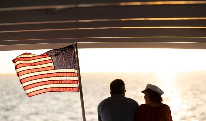 Couple on sunset cruise with American flag next to them