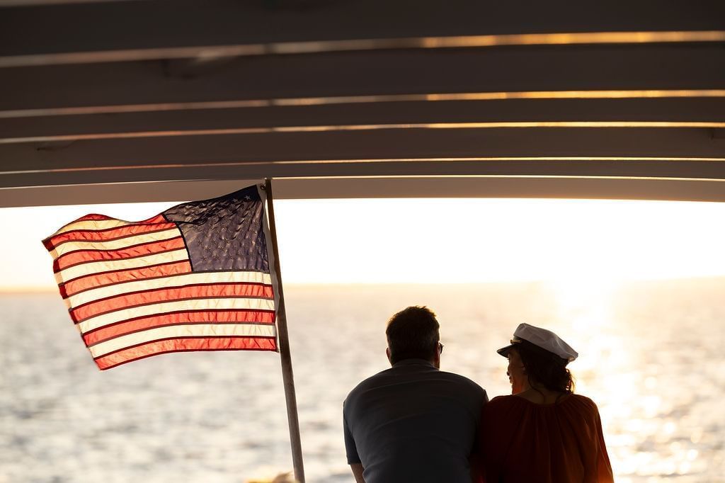 Couple on sunset cruise with American flag next to them