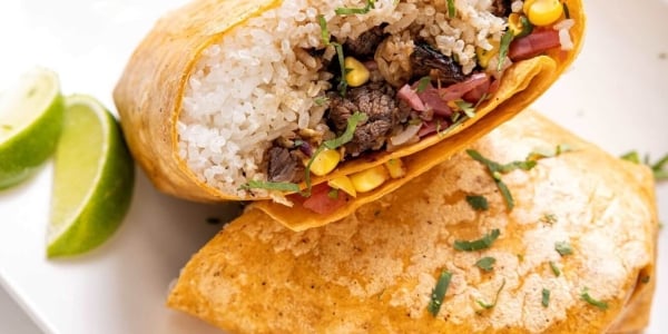 Burrito split in half on a plate with slices of lemon