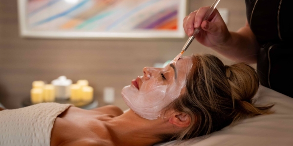 A woman receives a facial treatment from an aesthetician in a spa setting