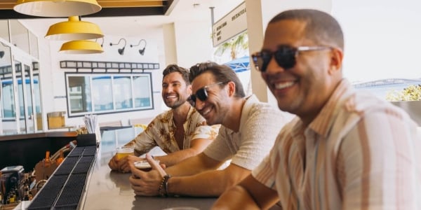 three men enjoying their drinks and having a laugh on bar counter
