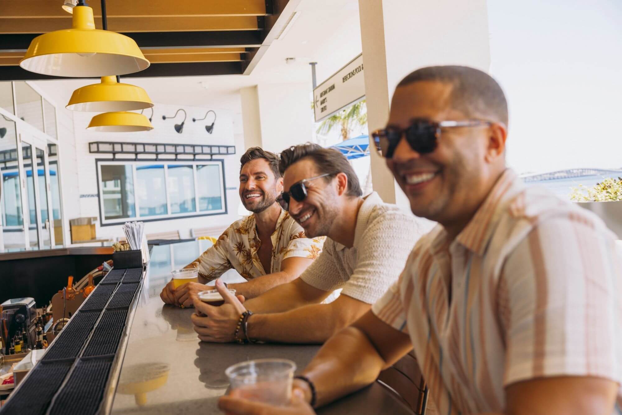 three men enjoying their drinks and having a laugh on bar counter