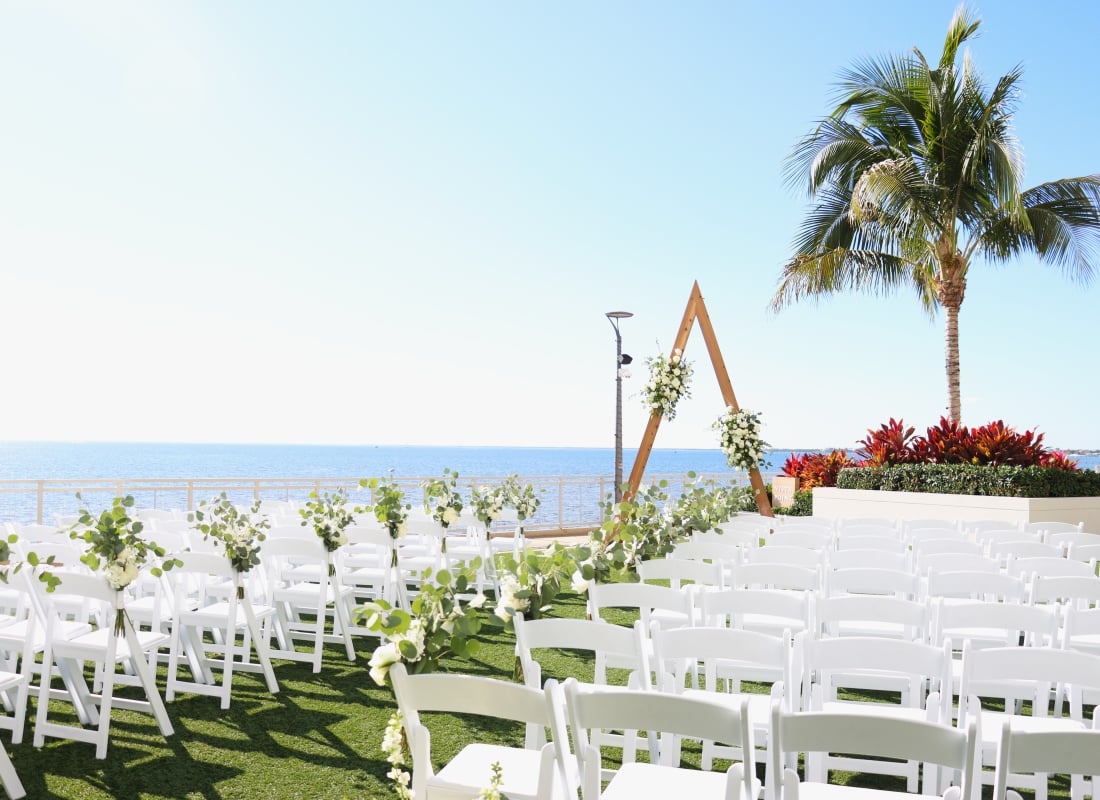 Waterfront wedding ceremony setup on the outdoor lawn at Sunseeker Resort, in Southwest Florida, with chairs, alter arch, and harbor views.
