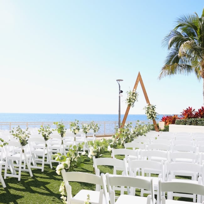 Waterfront wedding ceremony setup on the outdoor lawn at Sunseeker Resort, in Southwest Florida, with chairs, alter arch, and harbor views.