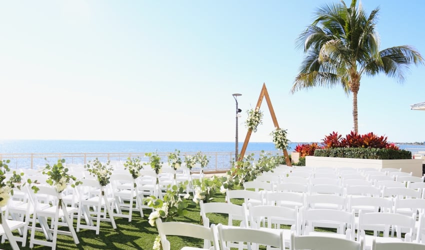 Waterfront wedding ceremony setup on the outdoor lawn at Sunseeker Resort, in Southwest Florida, with chairs, alter arch, and harbor views.