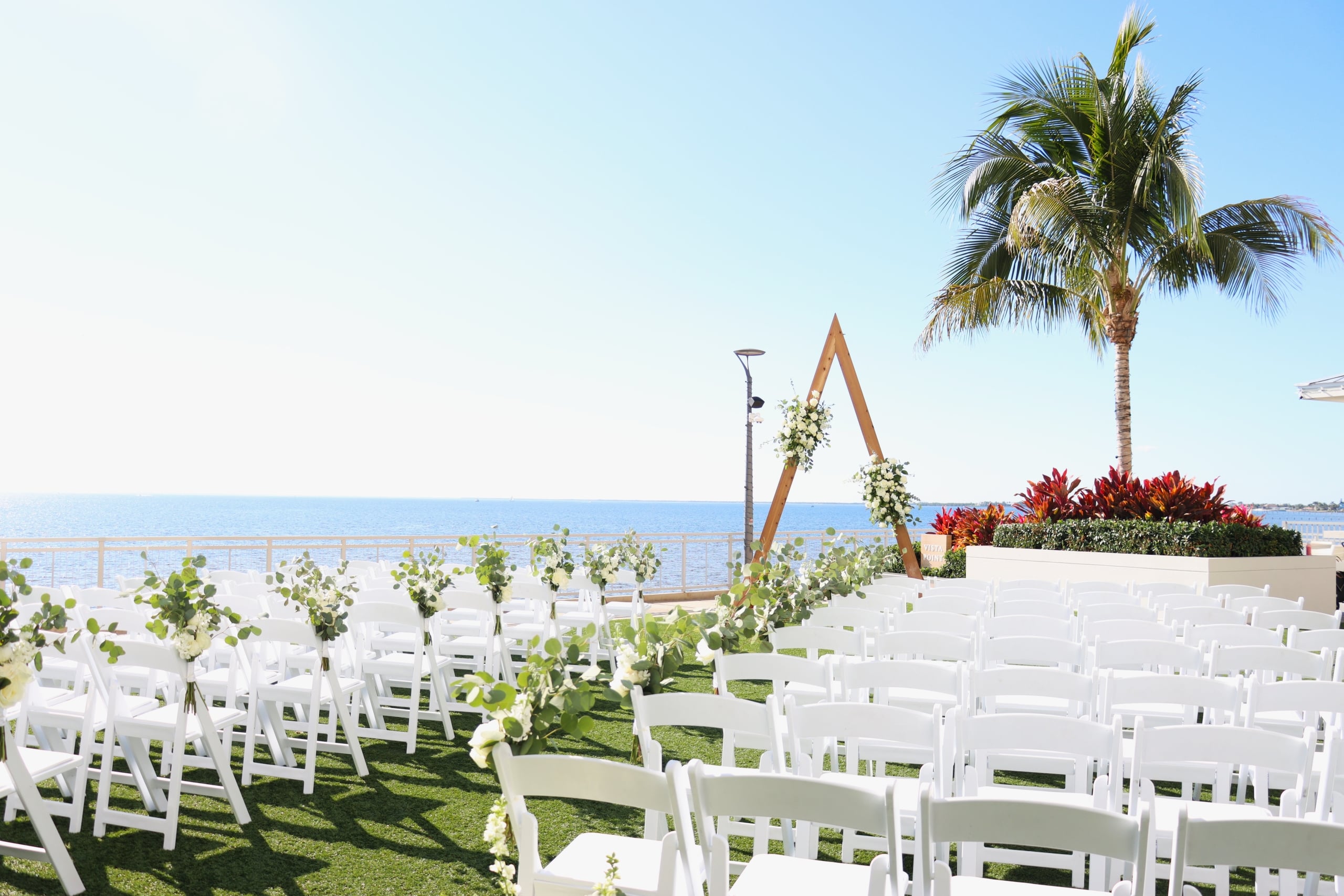 Waterfront wedding ceremony setup on the outdoor lawn at Sunseeker Resort, in Southwest Florida, with chairs, alter arch, and harbor views.
